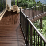 A wood deck attached to a house in a heavily-wooded area.