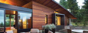 A modern home featuring wooden siding, glass windows, and black trim, showcasing a sleek and contemporary design. 